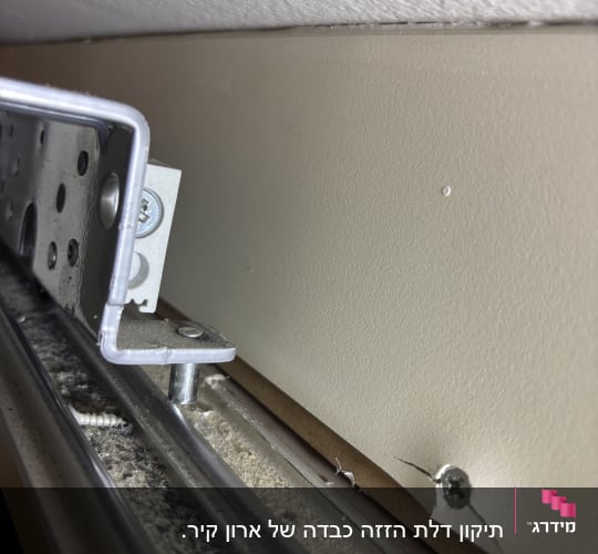 מסילת מתכת עם ברגים וקיר סדוק